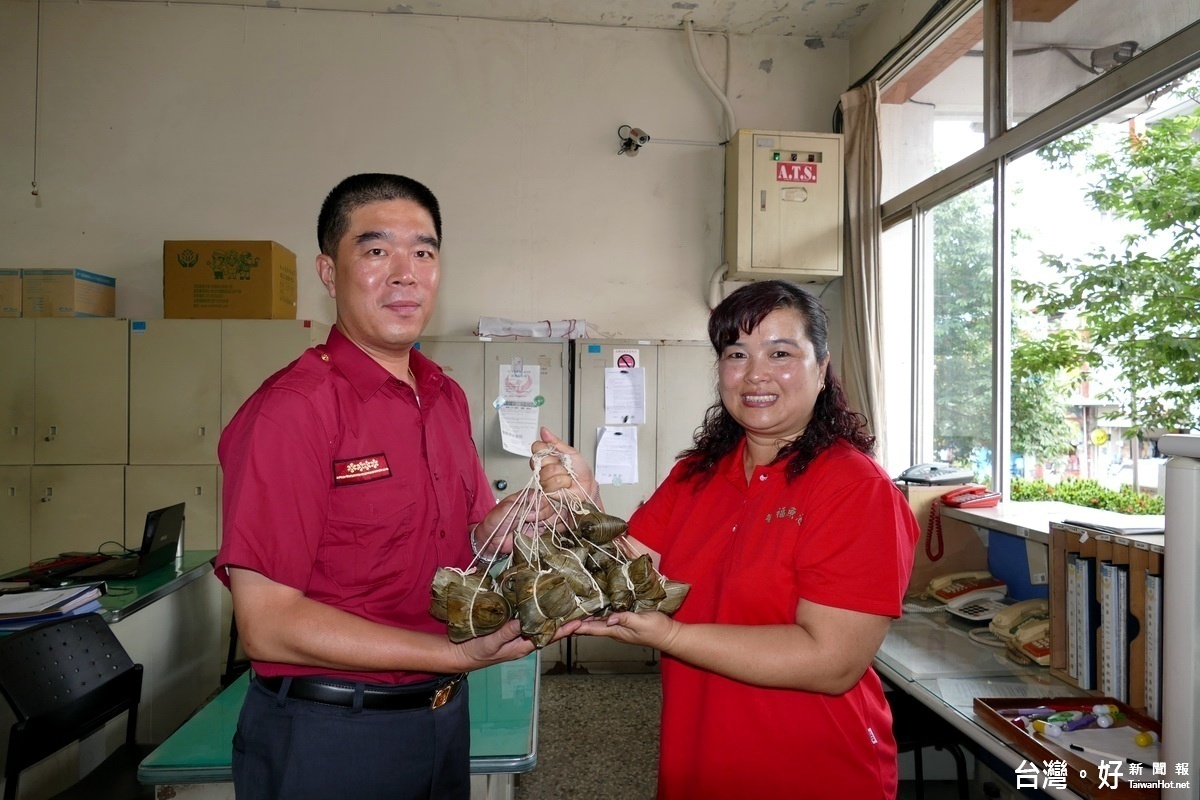 理事長王秋淑(右)將剛蒸好的粽子送到消防隊長手上，隊長開心的表示；這充滿愛心的粽子，一定相當好吃!