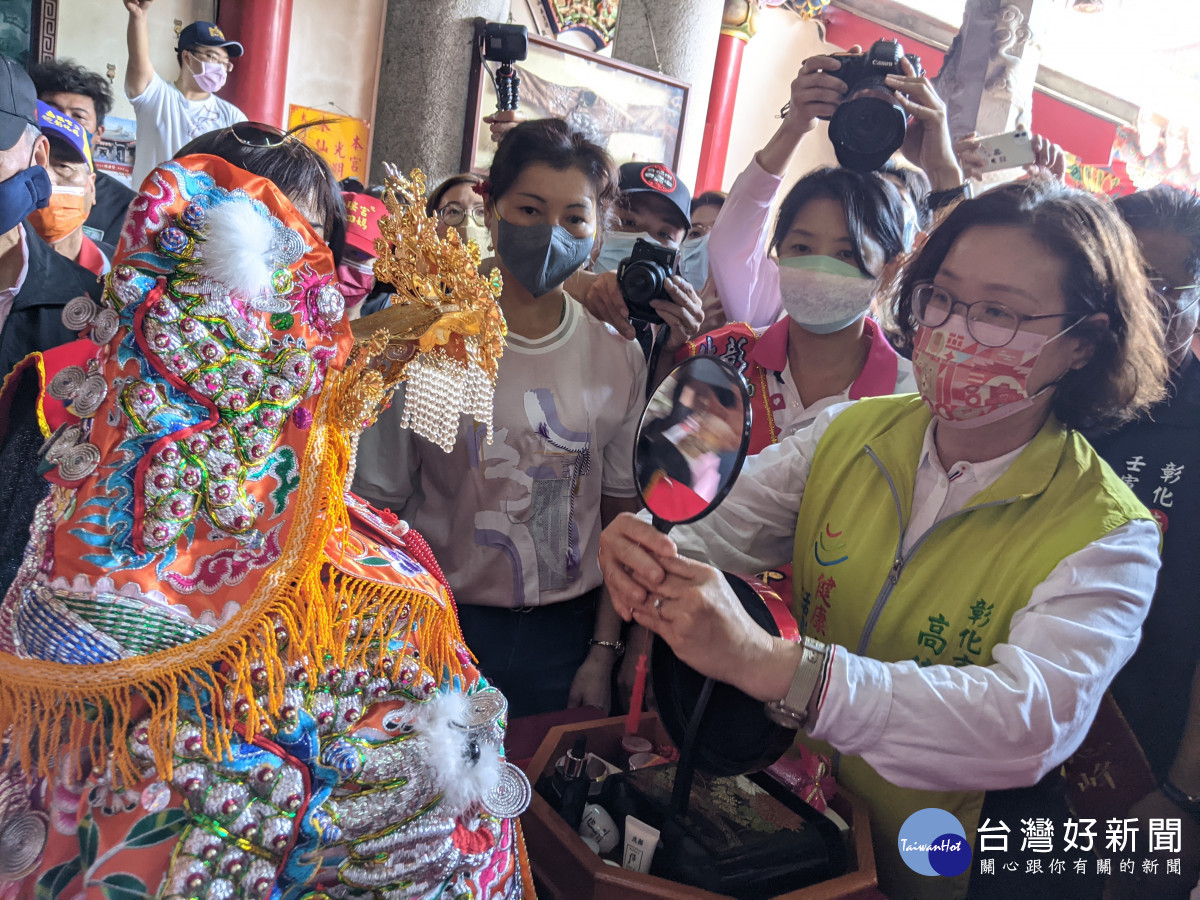 南瑤宮笨港進香主委市長林世賢的夫人高德耘為媽祖換穿新龍袍後,恭敬地持鏡子讓媽祖「照」。