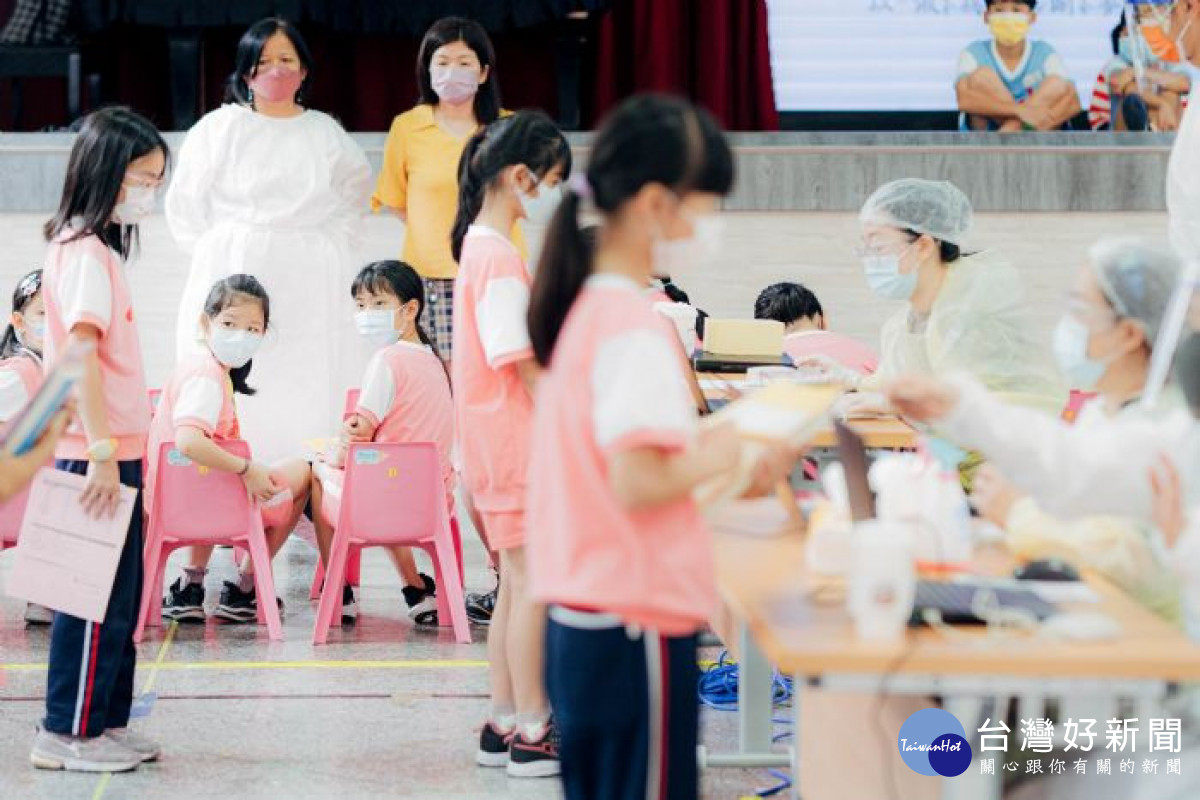 醫護人員協助國小學生第1劑疫苗入校接種作業。