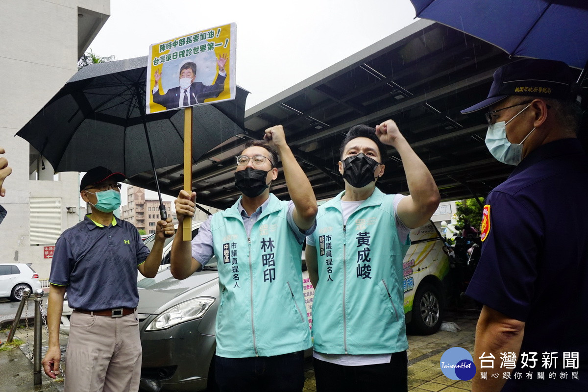台灣民眾黨兩位桃園市議員參選人黃成峻、林昭印，高舉標語牌並高喊「台灣單日確診世界第一，陳時中部長要加油」。