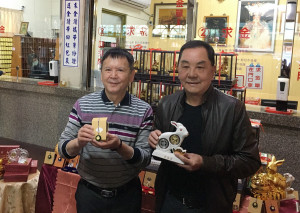 紫南宮主委莊秋安（右）與副主委莊志中展示兔年套幣造型與水晶項鍊。（記者扶小萍攝）