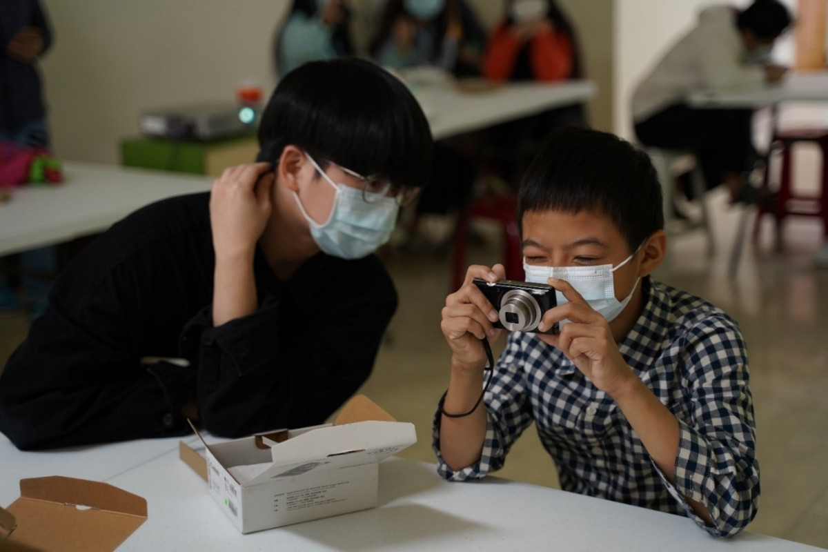 攝影志工陪伴孩子一起學習基礎相機使用規則(圖/社團法人臺灣兒少玩心教育協會提供)