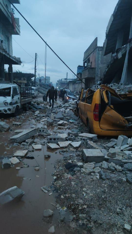 因地震造成街道兩旁的房屋損毀，連帶使停靠路邊的車輛被瓦礫砸毀
