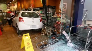白色自小客車失控撞進全聯超市，造成玻璃門碎裂，部分架上貨物散落一地／讀者提供