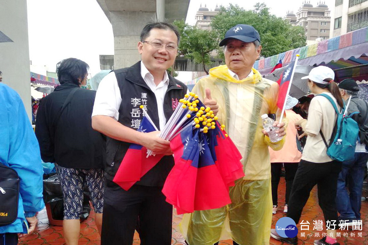 歡喜迎國慶，蘆竹區長李岳壇分送小國旗給參與健行活動的民眾。
