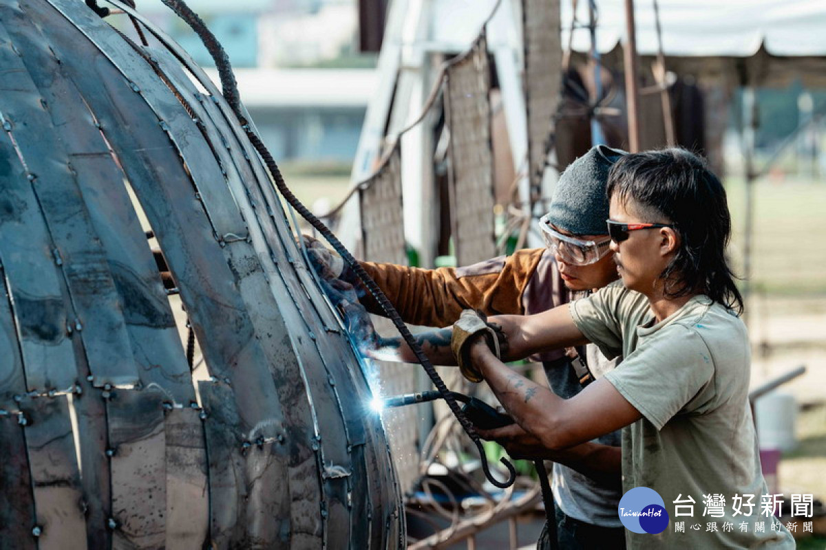 ▲拼體力也拼創意，藝術家陳俊憲(左)及助理在焊接火光中打造「戶外現地創作營」鋼雕作品《朝向十方之所》。