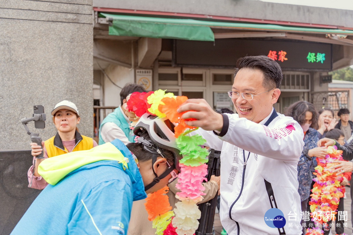 桃園市副市長蘇俊賓為「舞動后厝環台騎跡」單車環島凱旋歸來的小朋友帶上花圈。