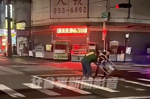 兩名男子手持鐵架，在路口疑似模仿「扶鸞問事」宗教儀式／陳致愷翻攝