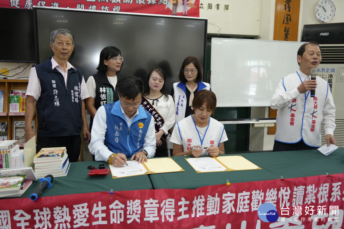 南投市長張嘉哲與周大觀讀出希望中心主任金馨梅簽署姊妹圖書館。（市公所提供）