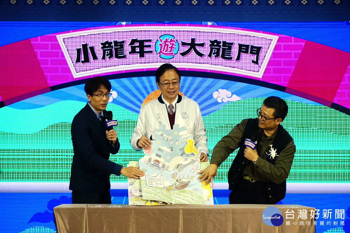 桃園市長張善政與摺紙藝術家洪新富、插畫家蕭民遠共同展示說明小龍年遊大龍門「非來BOOK立體摺頁」。