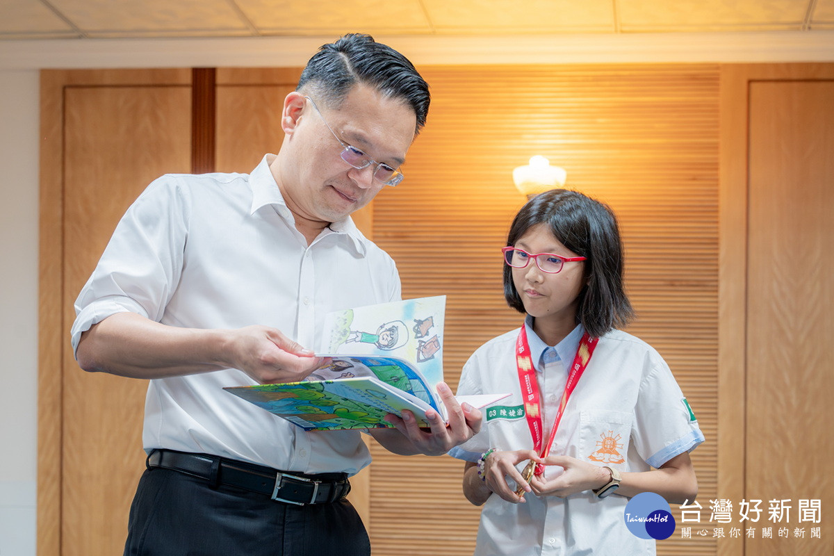 大崗國中陳婕渝同學將小繪本贈送給桃園市副市長蘇俊賓。
