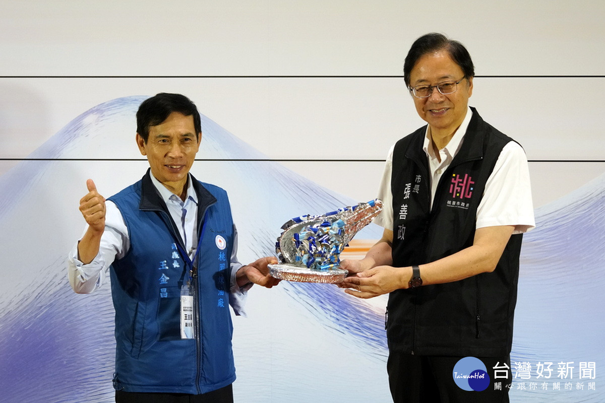 桃園市長張善政以海廢再生藝術品致贈認養企業。<br />
