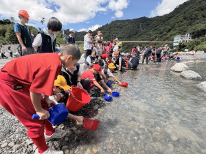 大甲溪發電廠黃陵育廠長偕同在地機關、民意代表、學童及電廠同仁於岸邊將魚苗慢慢放流進大甲溪。