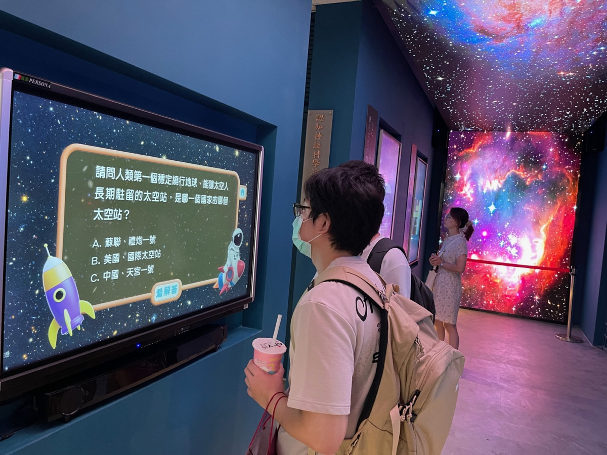 參觀民眾於「星空走廊」中央參與「太空天文大考驗」，在輕鬆問答中加深對天文與太空知識的理解。