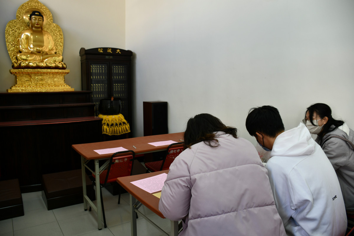 考生在菩薩像前靜心抄寫心經。圖／彰化市公所提供
