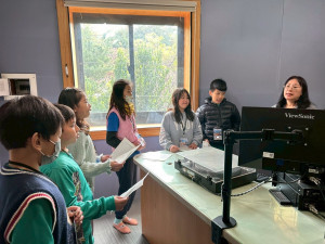 課程的高潮來到專業錄音間。學生戴上耳機、面對專業麥克風，親自操作直播設備進行。圖／福德國小提供