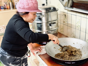 桃園在地粄食職人巫貞錦以香菇、肉末、蝦米等配料拌炒鹹年糕內餡，展現傳統工序對火候與材料比例的細緻掌握。