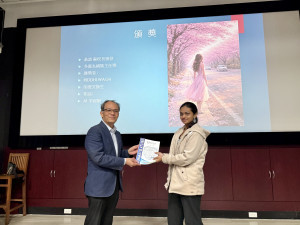 弘光科大校長蘇弘毅（左）頒獎給印度交換學生 Riddhi Anirudha Wagh（右），她的AI平面類作品（螢幕上顯示）獲得系主任獎。
