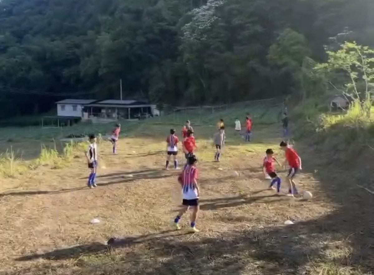學童在簡陋的土地上踢球。（趙榮瑞提供）