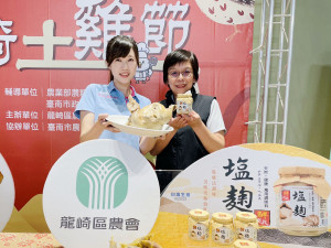 龍崎區農會總幹事林韋如（左）與臺鹽品牌行銷處長陳美文（右）展示以臺鹽「鮮選我塩麴」醃製料理的龍崎跑山土雞，共同推廣在地農產。