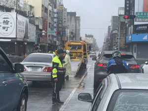 嘉義市南門派出所警員林義倫、簡睿羽冒雨協助移置拋錨車輛，指揮交通疏導車流／警方提供