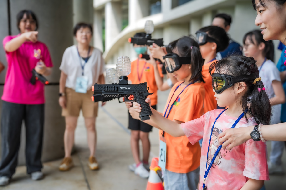 學童在志工的安全引導與鼓勵下,體驗水彈槍射擊活動。(元智大學校友總會提供)
