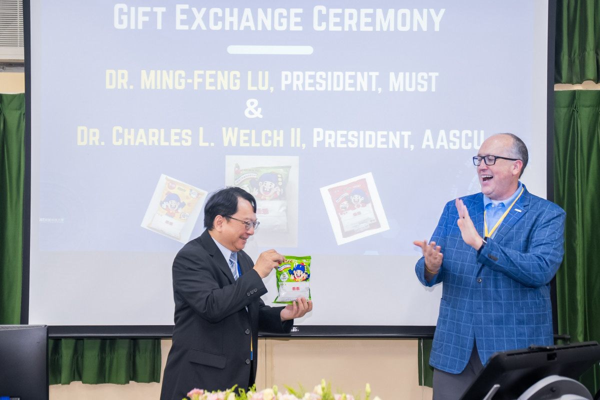 明新科大校長呂明峯(左)致贈綠色包裝「乖乖」予AASCU主席 Dr. Charles L. Welch II(右),並分享臺灣科技圈祈求機台「乖乖運轉」的趣味文化。