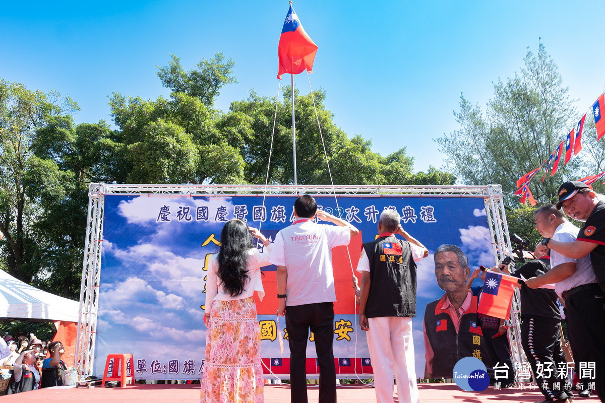 桃園市長張善政偕同夫人張琦雅及「國旗屋」主人張老旺於升旗典禮中向國旗致敬。<br />
