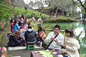 參與櫻花茶會的遊客，在湖畔品茗，分享茶師們的茶道精神。