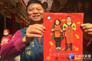 方一峰和往年般拿著大紅海報向鄉親賀年，左上方還有國民黨黨徽。(圖/記者黃芳祿攝)