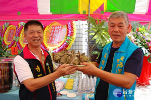 台南市第二選區市議員參選人方一峰(左)把象徵中「包中」的粽子贈送給安西里長參選人吳璨輝。(圖/記者黃芳祿攝) 