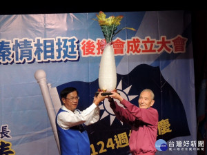 資深黨員厲寶全贈好彩頭予林明溱。（記者扶小萍攝）
