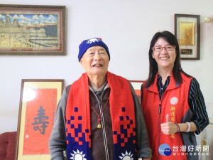  藍組長替嚴爺爺戴上輔導會致贈之紀念飾品及榮民榮眷基金會製發之國旗圍巾、毛帽，爺爺喜悅之情溢於言表