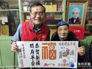 榮民書畫家吳偉烈(右)致贈年畫予新北市榮民服務處林火土處長(左)合影