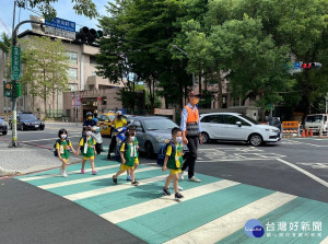 稽查人員扮演道路交通安全天使，帶領幼兒穿越馬路，提醒馬路如虎口，行走不嘻戲、不滑手機