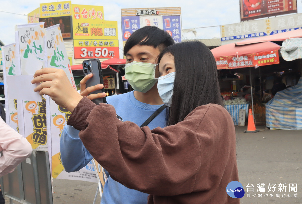 遊客獲贈摸彩券拍照留念。（記者扶小萍攝）