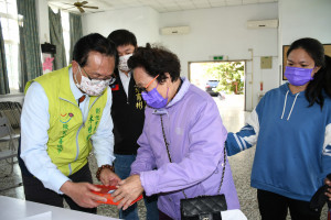 林世賢市長在阿夷里社區活動中心幫忙長者收好已領到的春節敬老禮金。圖／彰化市公所提供