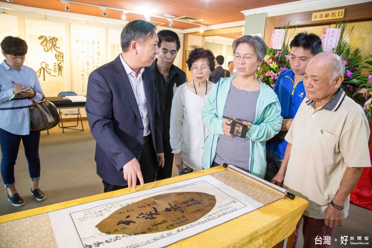 董事長龔忠輝向參展來賓說明書寫在芭蕉葉上的書法。(記者蘇榮泉 攝)