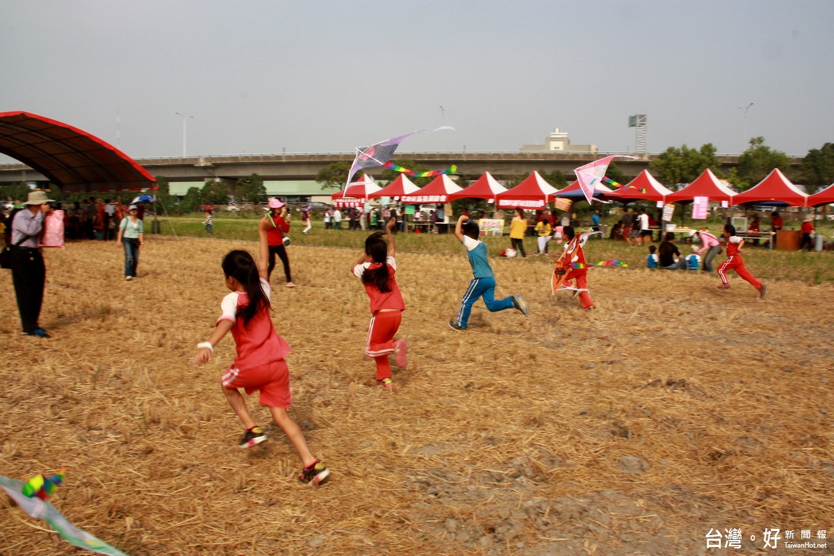 學童在稻田裡盡情奔跑放風箏。（記者扶小萍攝）