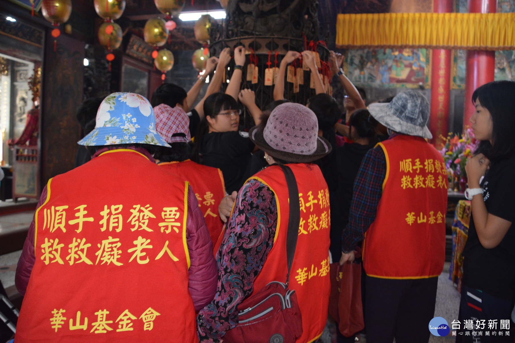 西港區長者寫下祈福牌,由西港天使站志工幫忙掛在慶安宮大殿龍柱上祈福。(記者/黃芳祿攝)