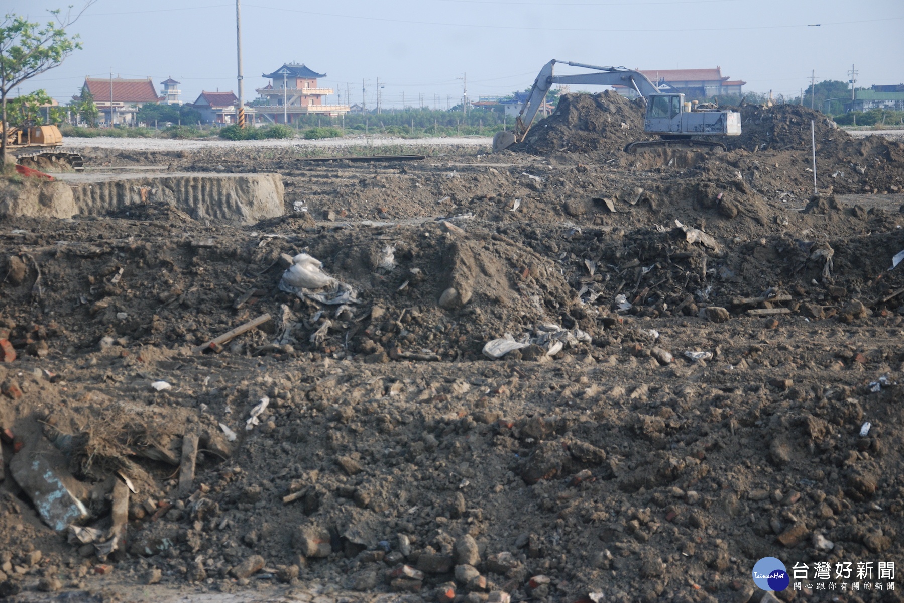 台南七股龍山區興建中的黃昭堂紀念公園,里民發現填土過程中夾帶事業廢棄物,經了解是水利局提供土方,里民以影響健康為由要求即日起停工,遠處為停歇未再作業的堆土機。(圖/記者黃芳祿攝)