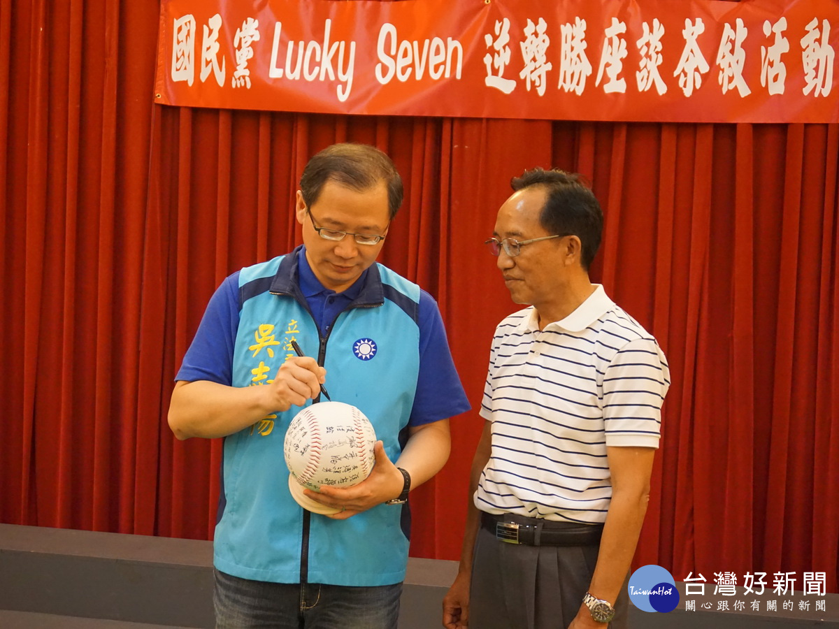吳志揚在象徵黨代表精誠團結的大型棒球上簽名。