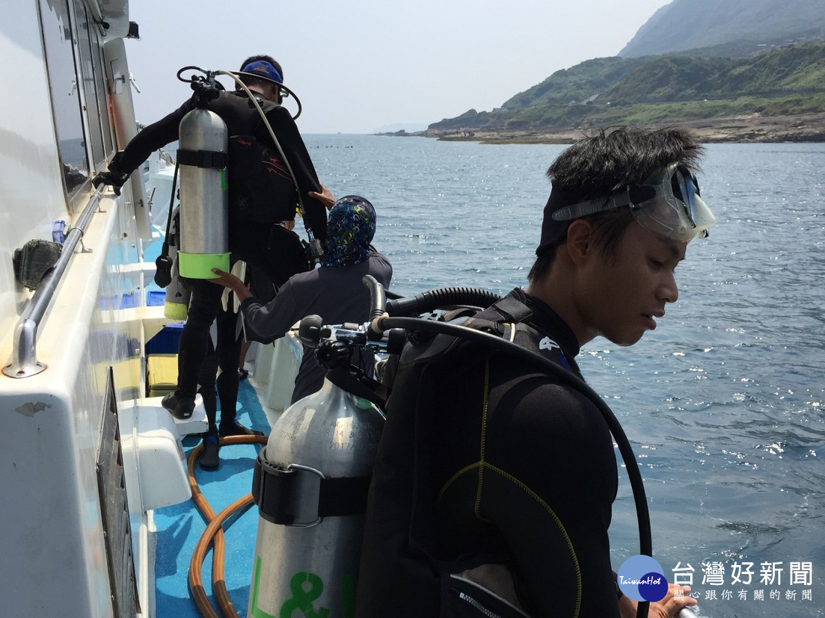 潛水員們揹著裝備準備下水淨海