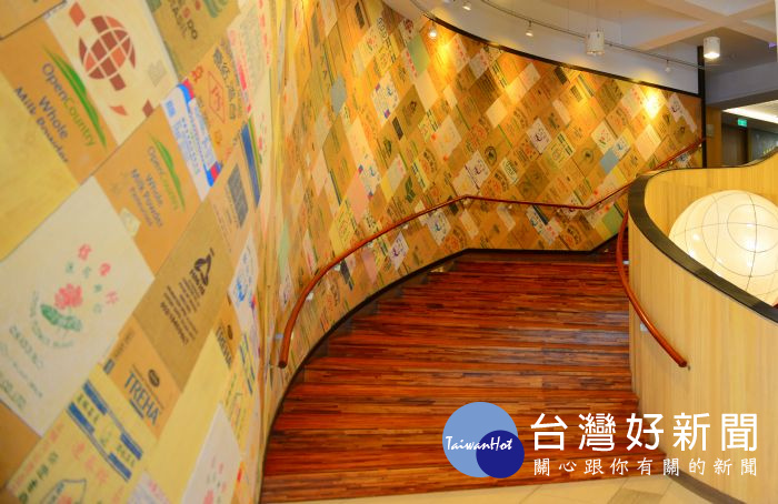 「再生藝術牆」的土黃色不是來自油漆，而是一個個拼貼的原料包裝袋 。 