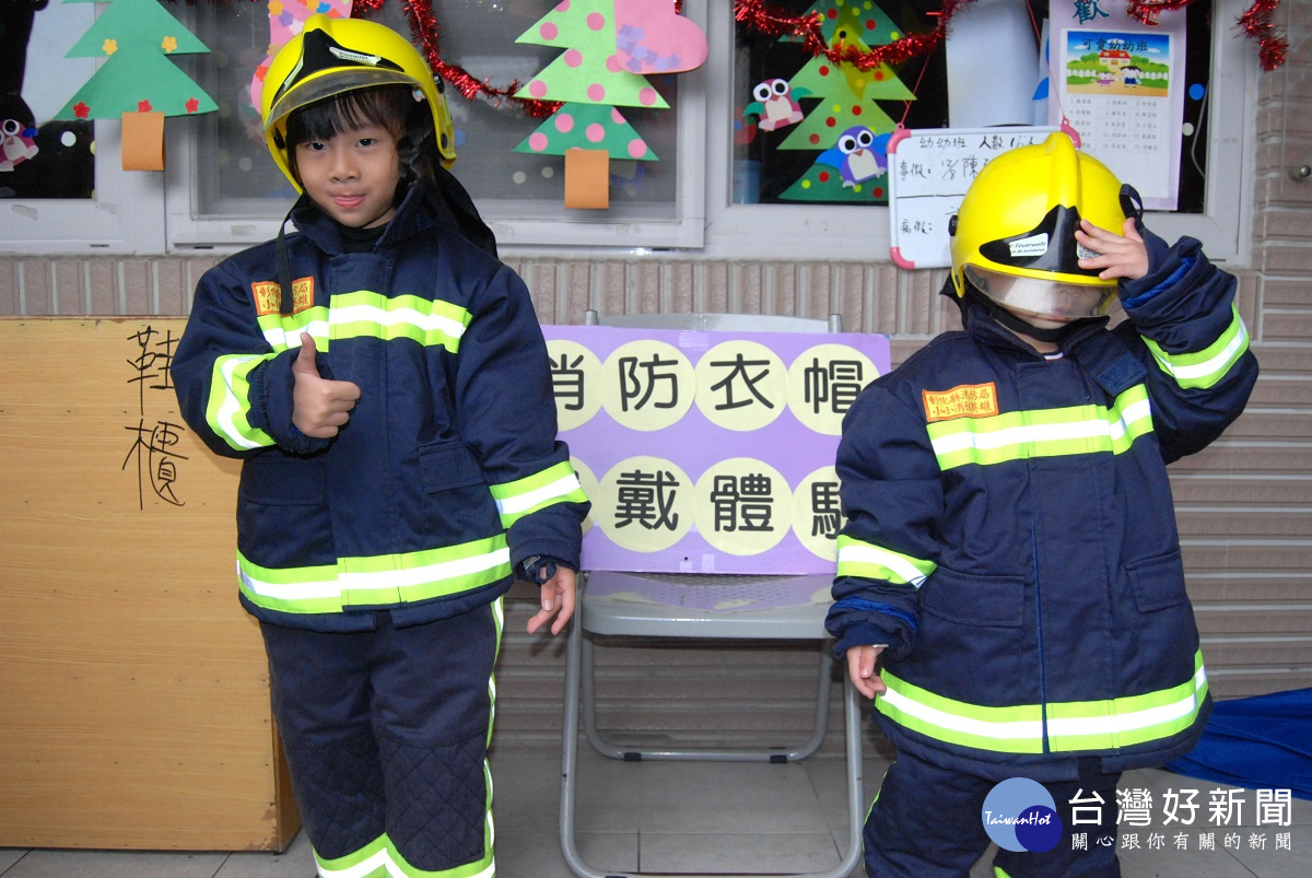 消防衣穿戴體驗-左邊的小朋友有模有樣右邊的小朋友則調皮將帽子蓋住臉。