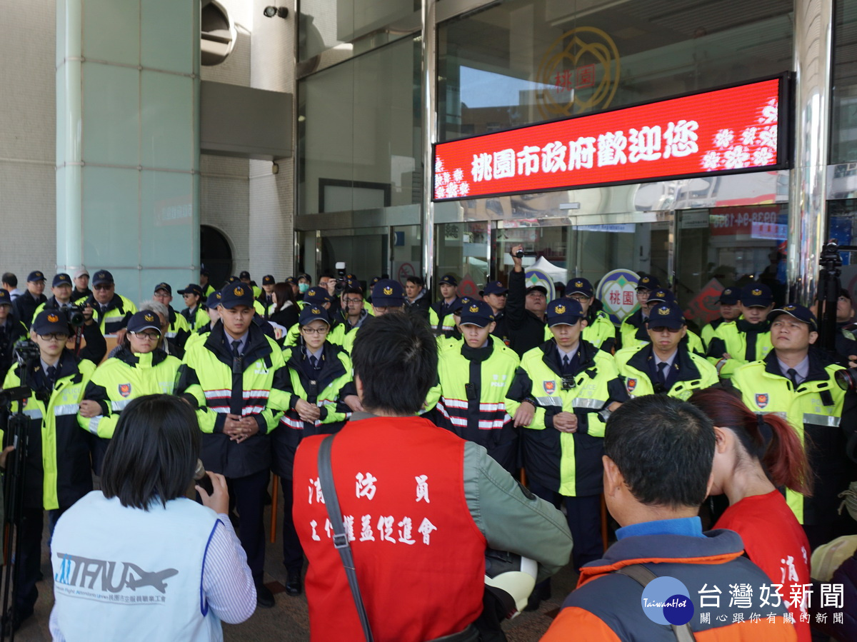 桃園警方以違反集遊法派出警力築成人牆,禁止陳情人等進入桃園市政府,與牆上電子看板「桃園市政府歡迎您」形成強烈對比。