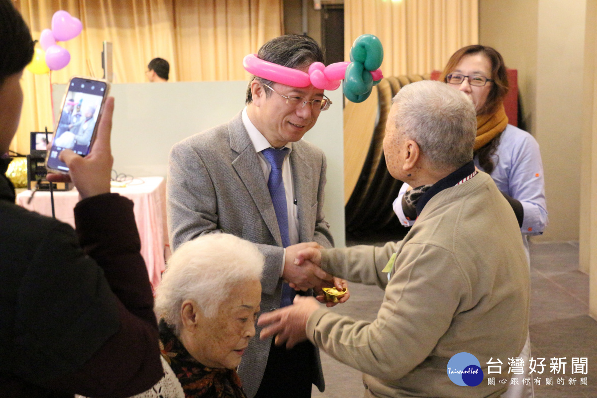 圖片說明3：剛到任一天的嘉基姚維仁院長(頭戴粉紅、綠色氣球帽者)致贈「祝福金元寶」給到場的長輩。