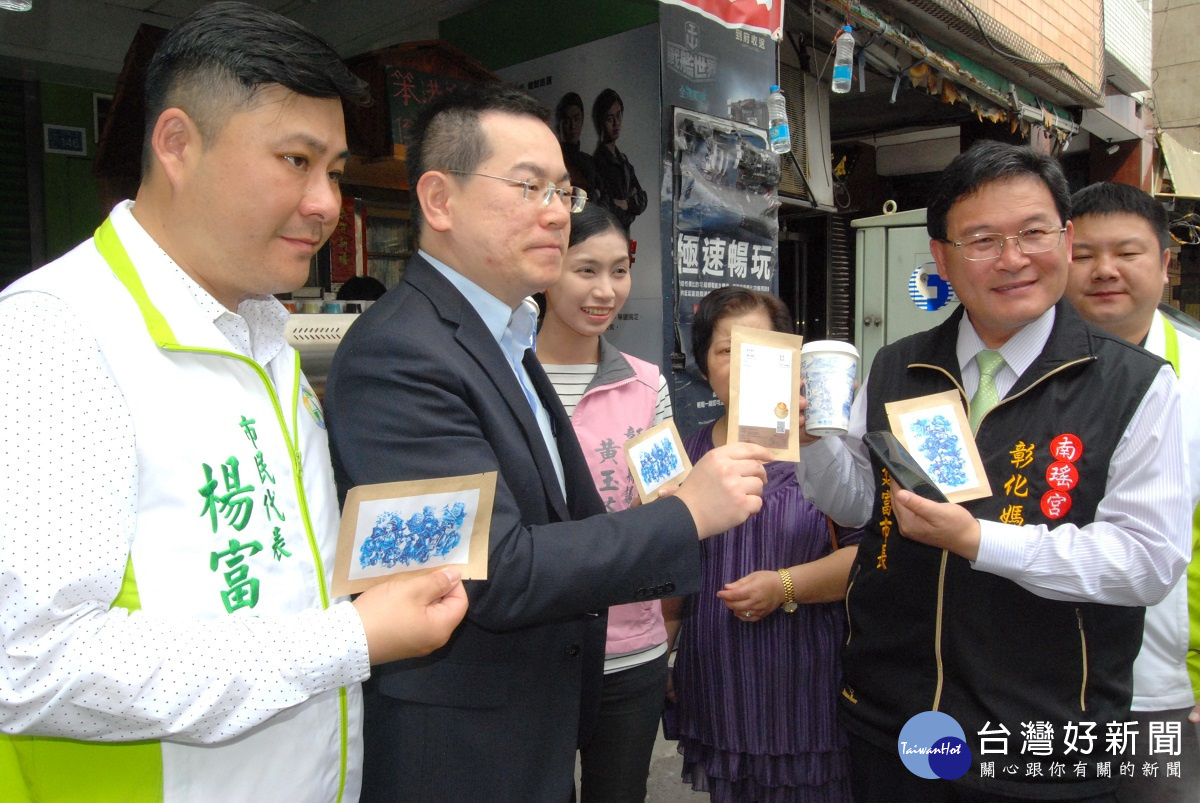 陳俊德醫師(左2)展示內附咖啡包的明信片為今年笨港進香限量紀念品。