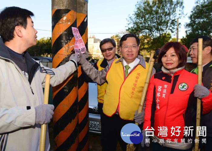 鄭文燦市長與環保志工及居民一起打掃環境，撕除違規小廣告單。