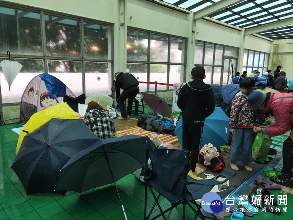 桃園市立游泳池休息區漏水連連,選手及家長們緊急利用雨傘來擋雨。